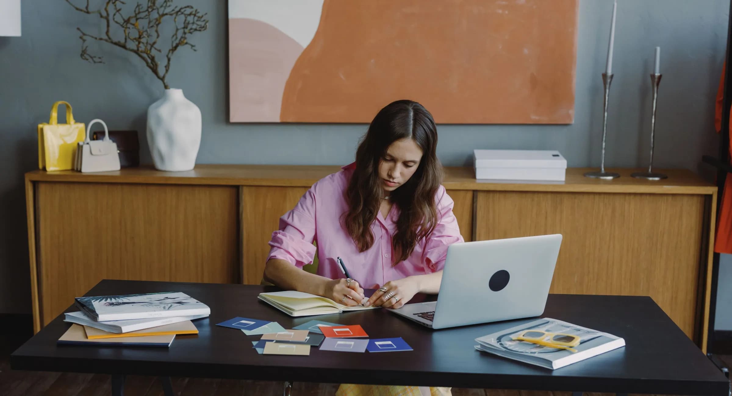A designer sketching at her desk beside a laptop